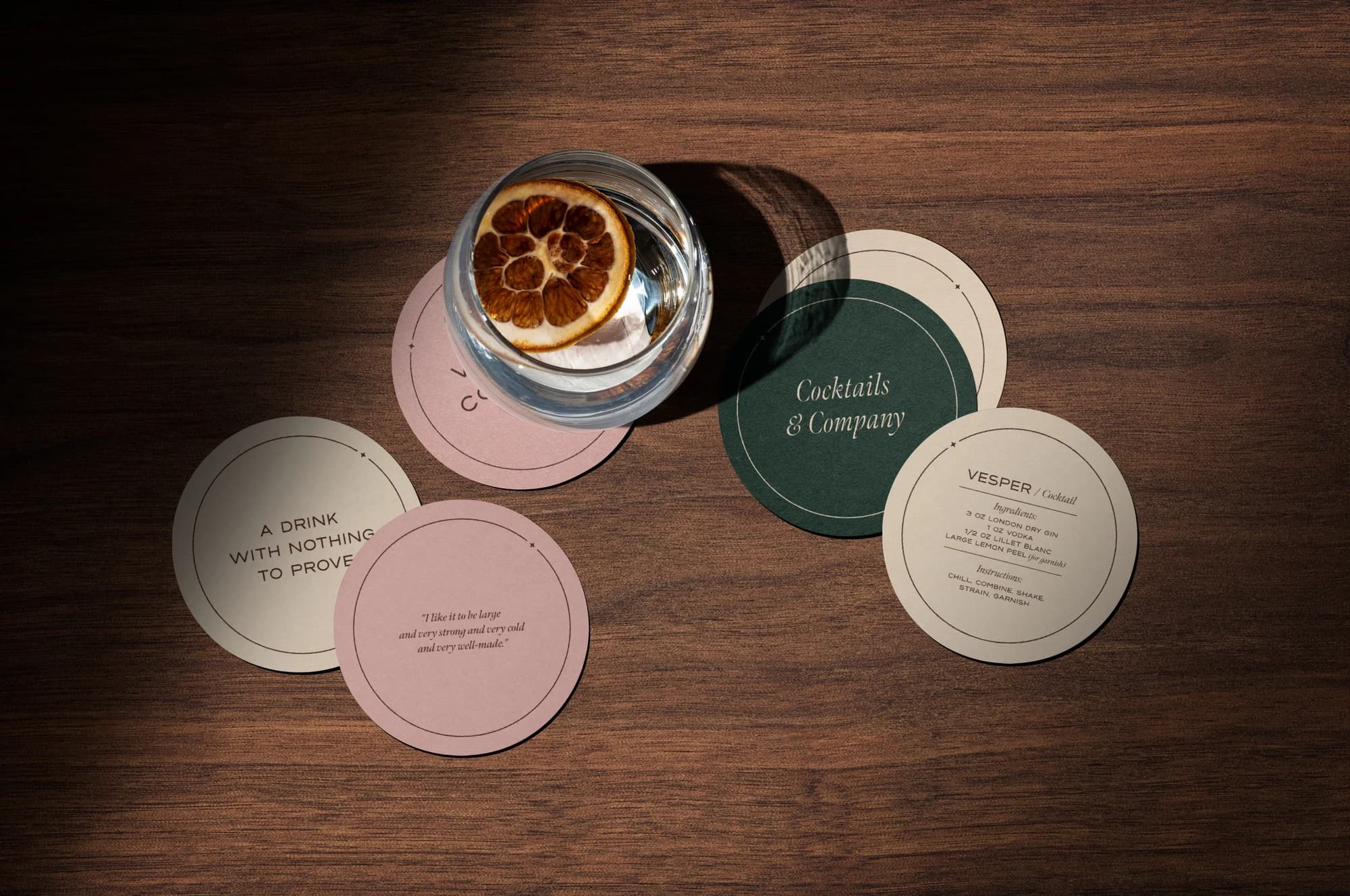 Cocktail and Vesper coasters arranged across a dark wood table
