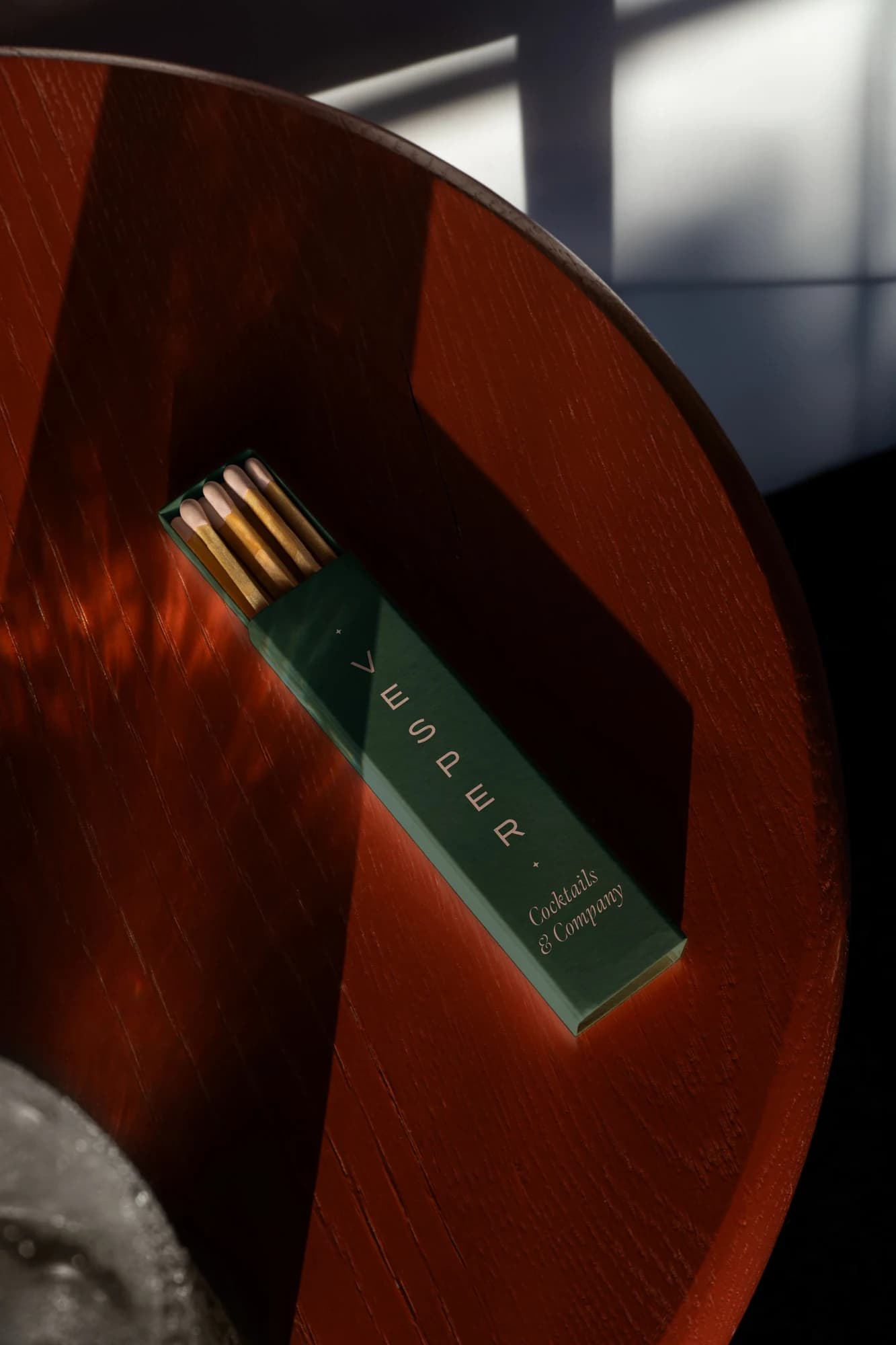 Green Vesper matchbox on a red wood table